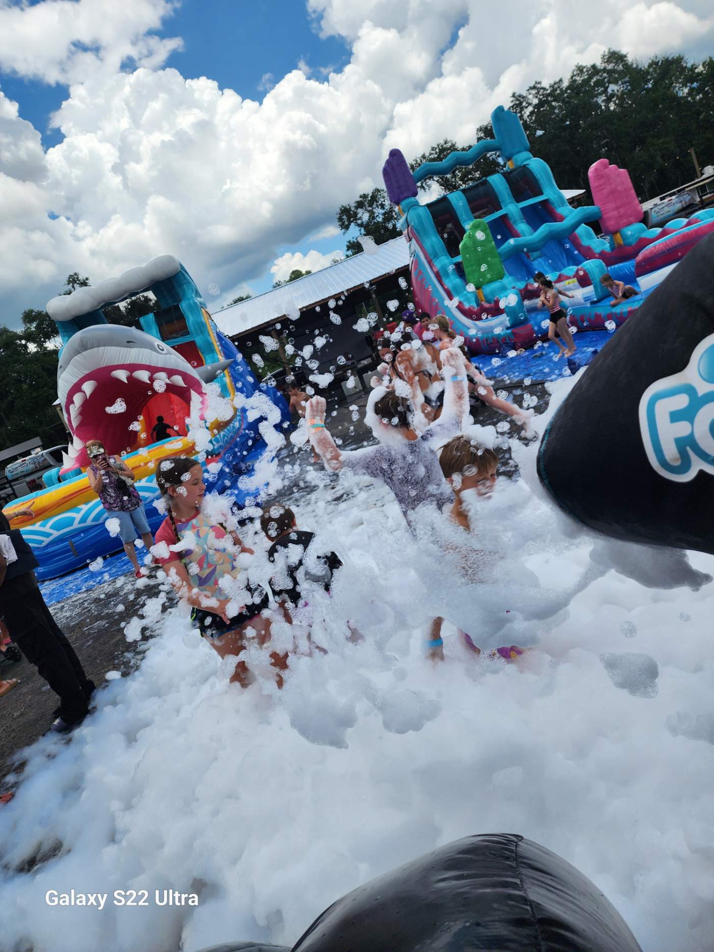 Foam party guests playing near a waterslide and bounce house in Lakeland, FL